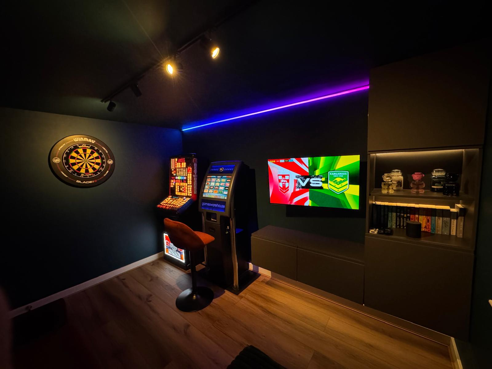 Home cinema and games room with wall-mounted TV, colour-changing LED strip lighting and track spotlights